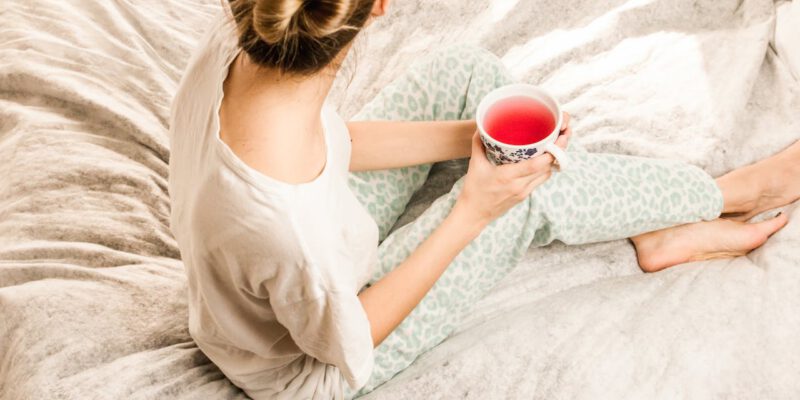 Vrouw zit op bed met wat drinken